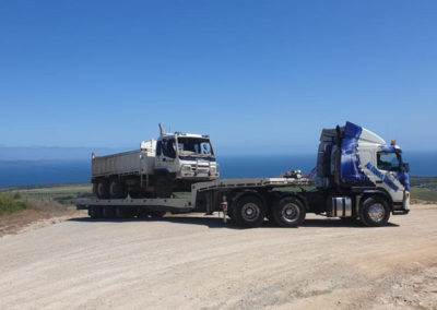 A large tilt tray tow truck loaded with a tandem tipper